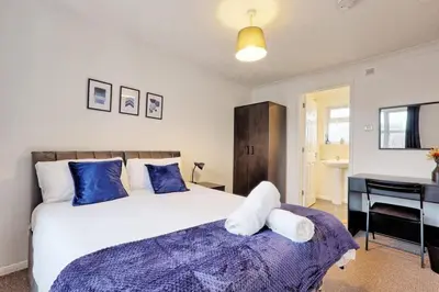 a bedroom with a large bed and a desk at Surehaven Stays 6 Bedroom House Great for Teams in Colchester