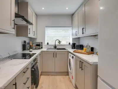 a kitchen with white cabinets and a sink and a dishwasher at Surehaven Stays 3 Bedroom House Braintree in Braintree
