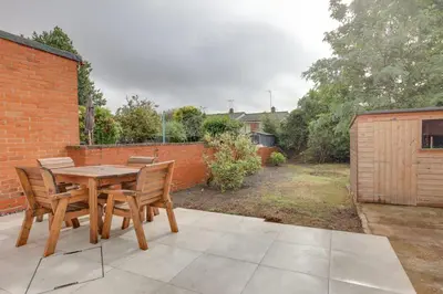 a wooden table and chairs on a patio at Surehaven Stays 3 Bedroom House Braintree in Braintree