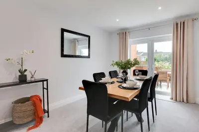 a dining room with a table and black chairs at Surehaven Stays 3 Bedroom House Braintree in Braintree