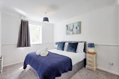 a bedroom with a bed with a blue blanket at Surehaven Stays 3 Bedroom House Braintree in Great Notley