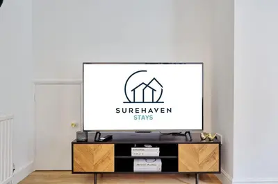 a tv screen on a stand in a living room at Surehaven Stays 3 Bedroom House Braintree in Great Notley