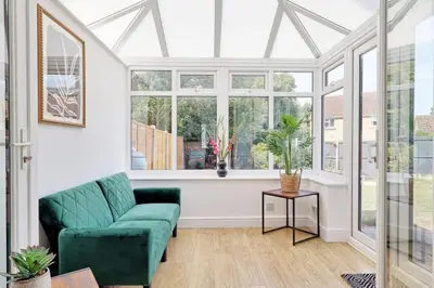 a living room with a green couch and windows at Surehaven Stays 3 Bedroom House Braintree in Great Notley