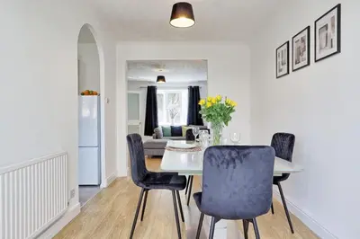 a dining room with a table and chairs and a couch at Surehaven Stays 3 Bedroom House Braintree in Great Notley