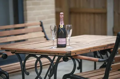 a bottle of wine on a wooden table with two wine glasses at Surehaven Stays 4 Bedroom House Braintree in Braintree
