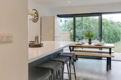 a kitchen with a counter and a table and stools at Surehaven Stays 4 Bedroom House Braintree in Braintree