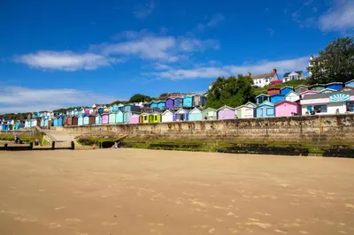 a row of colorful houses next to a beach at Lovely 8 Berth Caravan With Decking To Hire At Naze Marine In Essex Ref 17030Ga in Walton-on-the-Naze
