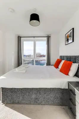 a bedroom with a large bed with a window at The Opulent Property Project ChelmsfordCityCentre 2Bed2Bath FreeParking Balcony in Chelmsford