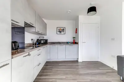 a white kitchen with white cabinets and wooden floors at The Opulent Property Project ChelmsfordCityCentre 2Bed2Bath FreeParking Balcony in Chelmsford