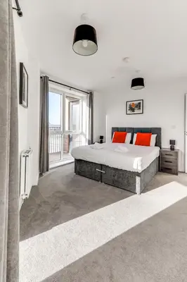 a bedroom with a large bed and a large window at The Opulent Property Project ChelmsfordCityCentre 2Bed2Bath FreeParking Balcony in Chelmsford