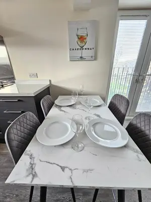 a marble table with two plates and wine glasses on it at Pancinos Guest House Newmarket High Street in Newmarket