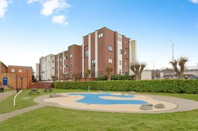 a park with a pond in front of a building at Pancinos Guest House Newmarket High Street in Newmarket