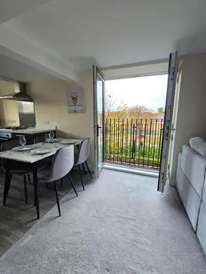 a room with a table and a kitchen with a sliding glass door at Pancinos Guest House Newmarket High Street in Newmarket