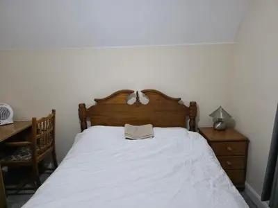 a bedroom with a white bed with a wooden headboard at Near Colchester hospital in Hythe