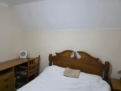 a bedroom with a bed with a wooden headboard at Near Colchester hospital in Hythe