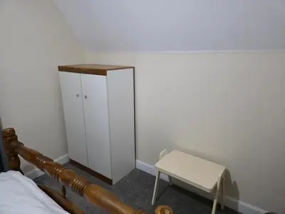 a bedroom with a bed and a white cabinet and a chair at Near Colchester hospital in Hythe