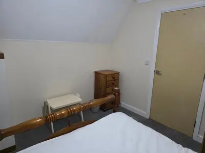 a bedroom with a bed and a dresser and a door at Near Colchester hospital in Hythe