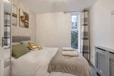 a bedroom with a large white bed with a window at Beautiful 3 bedroom house, Laindon, Basildon. in Laindon