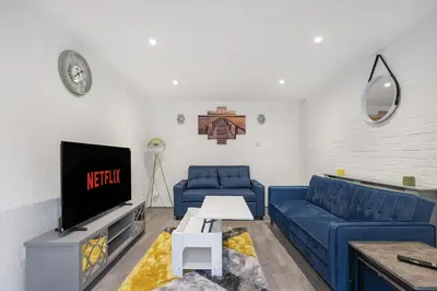 a living room with a blue couch and a tv at Beautiful 3 bedroom house, Laindon, Basildon. in Laindon