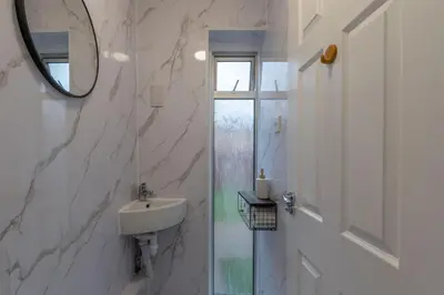 a white bathroom with a sink and a mirror at Beautiful 3 bedroom house, Laindon, Basildon. in Laindon