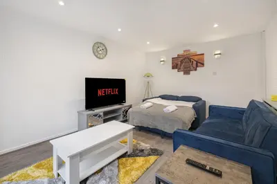 a living room with a blue couch and a tv at Beautiful 3 bedroom house, Laindon, Basildon. in Laindon