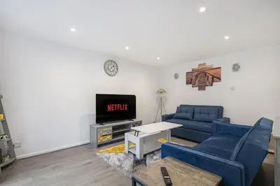 a living room with a blue couch and a tv at Beautiful 3 bedroom house, Laindon, Basildon. in Laindon