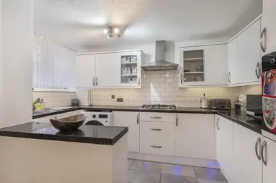 a kitchen with white cabinets and a black counter top at Beautiful 3 bedroom house, Laindon, Basildon. in Laindon
