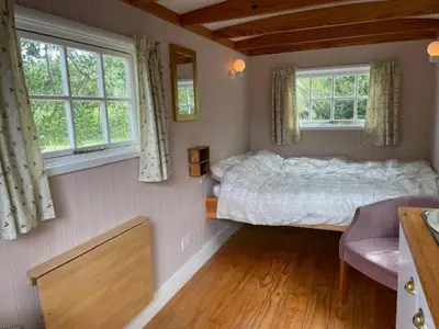 a bedroom with a large bed and two windows at Riverside Retreat in Little Baddow