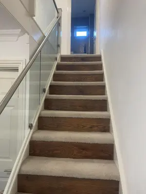 a staircase with wooden stairs and glass railing at Cassandra Homes in Nevendon