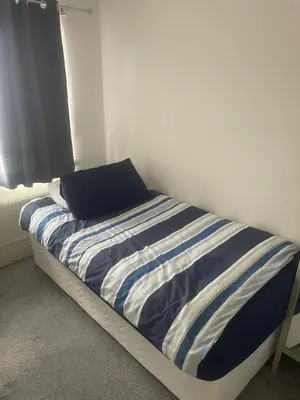 a bed with a blue and white striped comforter in a bedroom at Cassandra Homes in Nevendon