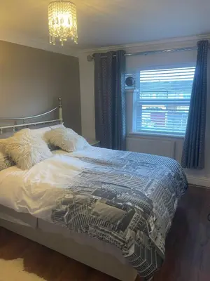 a bedroom with a bed and a window and a chandelier at Cassandra Homes in Nevendon
