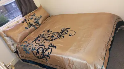 a bed with a brown comforter with a black design at Cassandra Homes in Nevendon