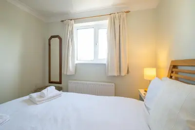 a bedroom with a bed with a mirror and a window at Rainbow Cottage in Thorpeness, Close to the Beach, Golf and the Country Club in Thorpeness
