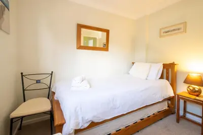a bedroom with a bed and a chair and a mirror at Rainbow Cottage in Thorpeness, Close to the Beach, Golf and the Country Club in Thorpeness