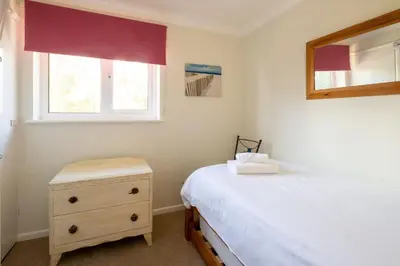 a bedroom with a bed and a dresser and a window at Rainbow Cottage in Thorpeness, Close to the Beach, Golf and the Country Club in Thorpeness