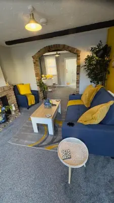 a living room with a blue couch and a table at Olivia's Cosy Cottage in Great Baddow