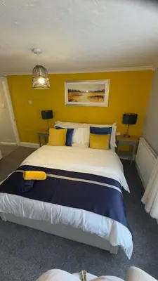 a bedroom with a large bed with blue and yellow walls at Olivia's Cosy Cottage in Great Baddow