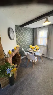 a dining room with a table and chairs and a clock at Olivia's Cosy Cottage in Great Baddow