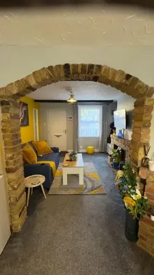 a living room with a blue couch and a brick wall at Olivia's Cosy Cottage in Great Baddow