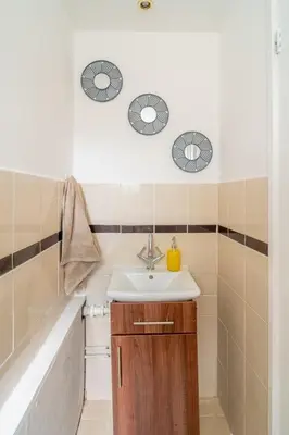 a bathroom with a sink and two mirrors at Spacious 3-Bed Home with parking in Lexden
