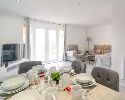 a dining room with a table and chairs and a tv at Spacious 3-Bed Home with parking in Lexden