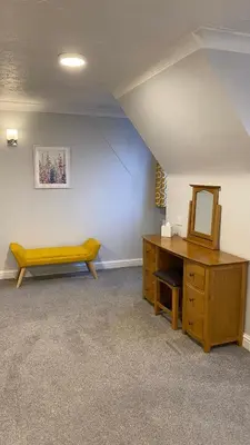 a room with a vanity and a mirror and a bench at The cottage in Bury Saint Edmunds
