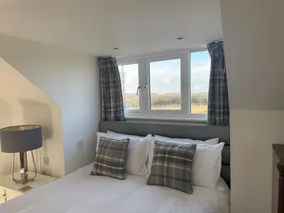 a bedroom with a bed with a window at Cottage on remote wild coast in Bawdsey