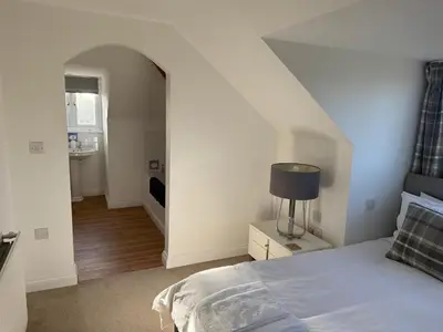 a white bedroom with a bed and a hallway at Cottage on remote wild coast in Bawdsey