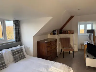 a bedroom with a bed and a desk and a chair at Cottage on remote wild coast in Bawdsey