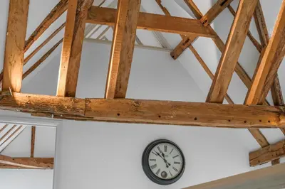 a clock on a wall in a room with wooden ceilings at Scotland Hall Barn, Stoke by Nayland, Suffolk in Stoke by Nayland