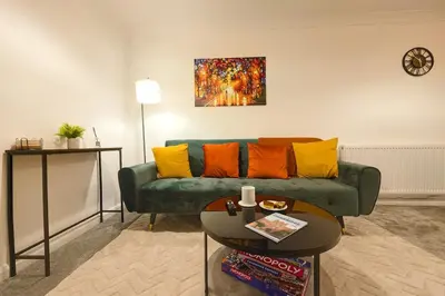 a living room with a green couch and a table at Nr Addenbrookes Large Hot Tub Stay Sleeps 10 in Barnwell Junction Station