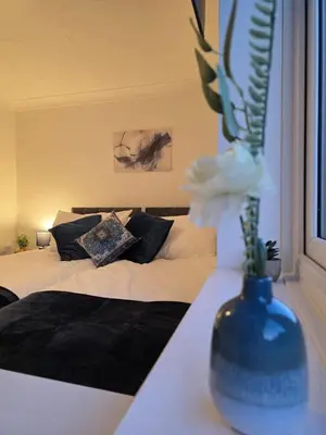 a bedroom with a bed with a vase with a flower at Nr Addenbrookes Large Hot Tub Stay Sleeps 10 in Barnwell Junction Station