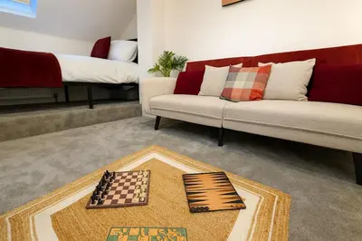 a living room with a couch and chessboard on a rug at Nr Addenbrookes Large Hot Tub Stay Sleeps 10 in Barnwell Junction Station