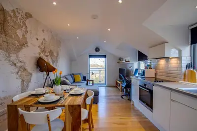 a kitchen and living room with a wooden table and a dining room at Stylish and Modern Flat with Free Parking - Pass the Keys in Cambridge